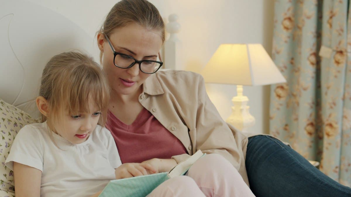 A mother and daughter reading together in bed at bedtime