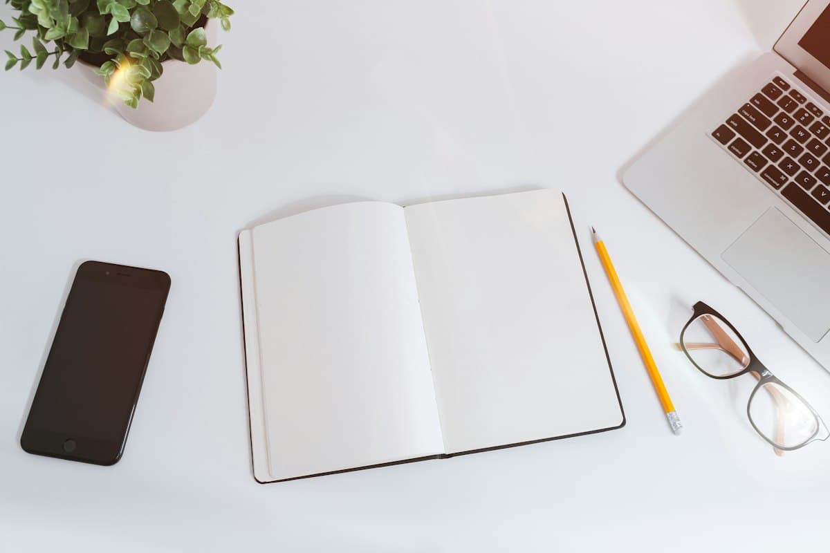 An open notebook, pencil and glasses on a tidy desk