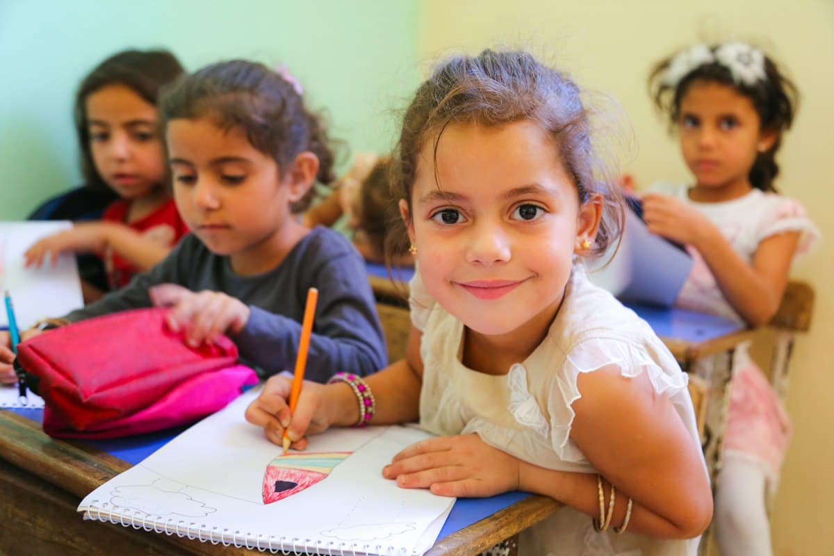 Young children drawing at their desks in a classroom